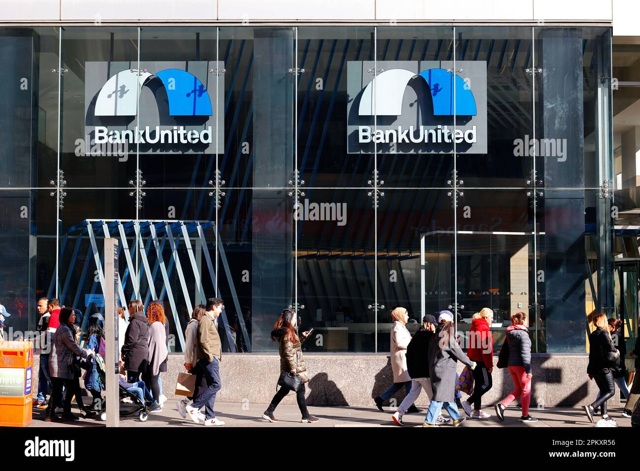 People walk past a BankUnited bank branch, 960 6th Ave, New York in Manhattan's Herald Square. Stock Photo