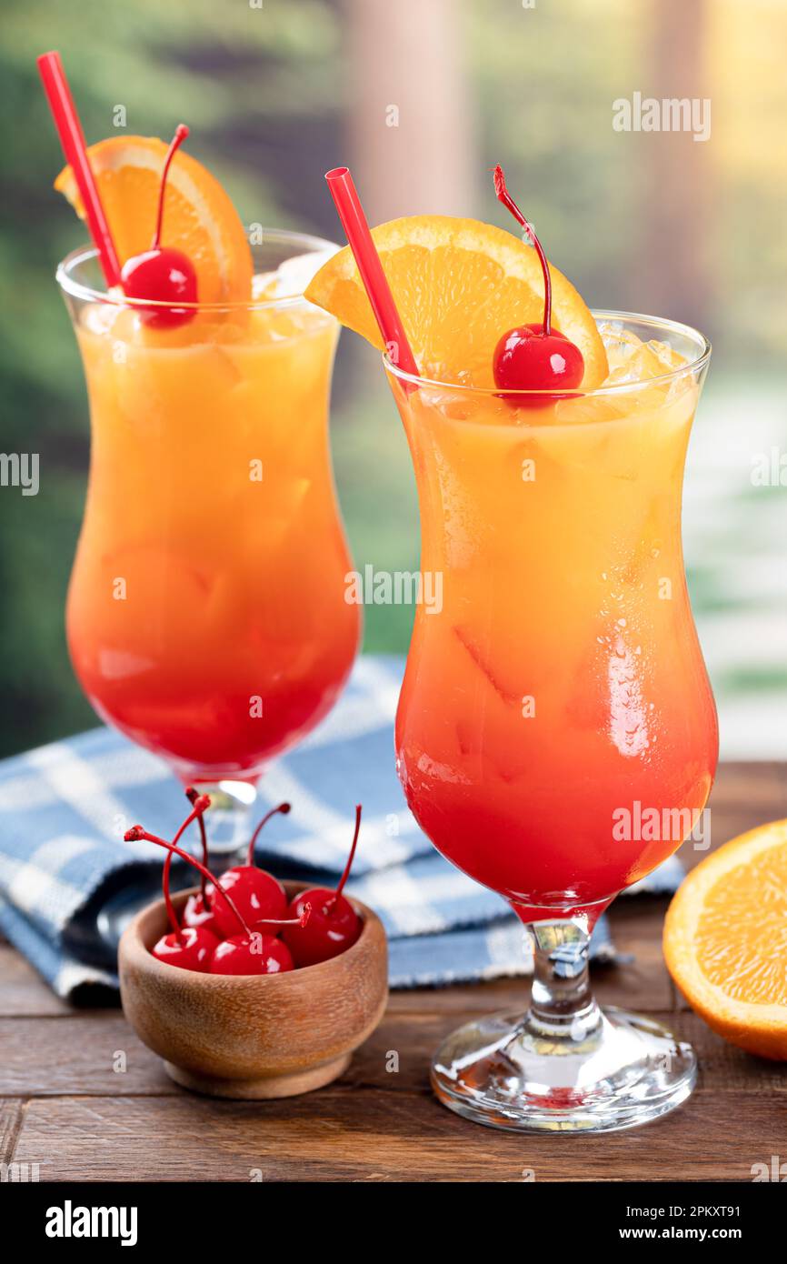 Tequila sunrise cocktail with orange slice and cherry on wooden table ...