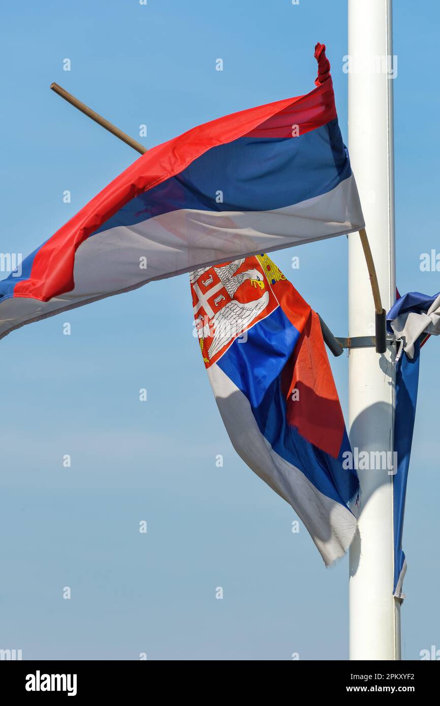 Torn and weathered flag of Serbia on a post waving in wind, selective focus Stock Photo