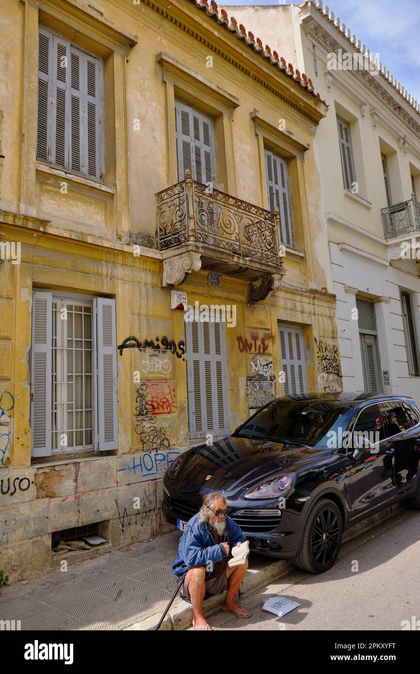 Homeless man begging next to a Porsche Cayenne in Athens Stock Photo