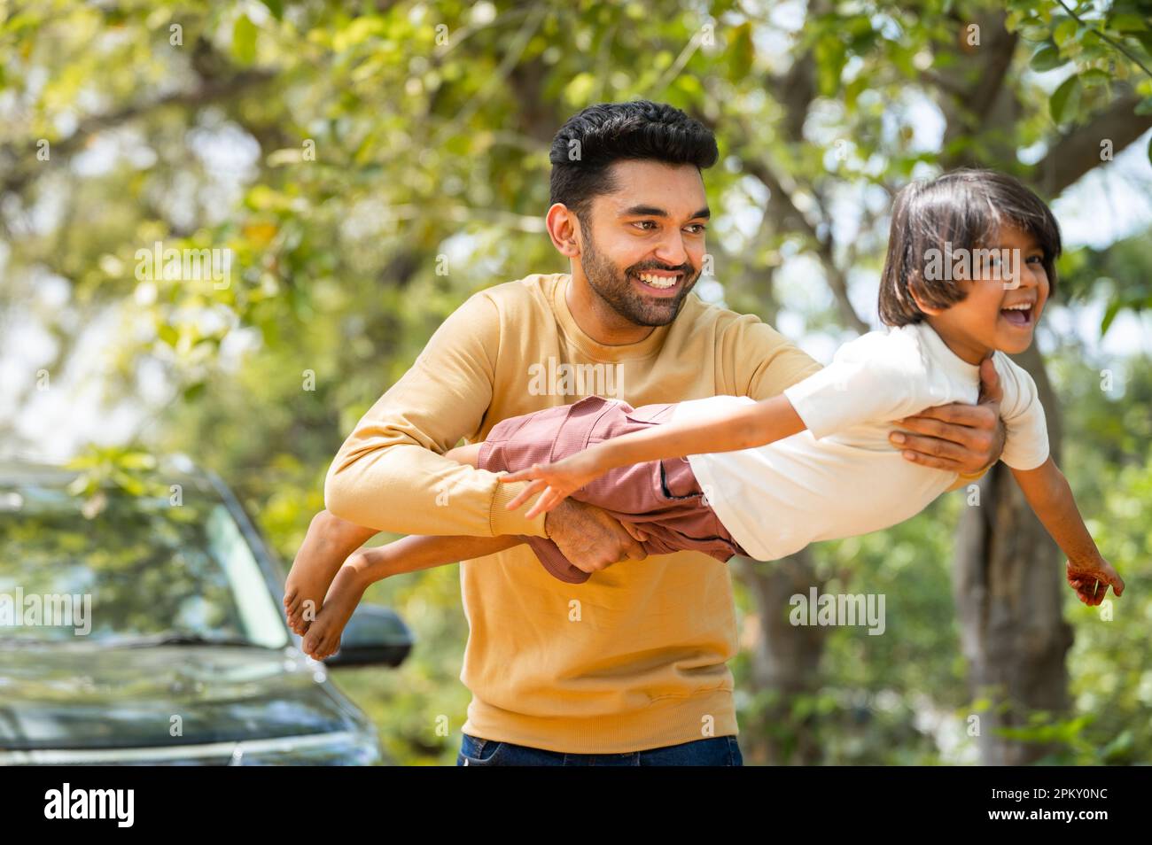 Happy young father playing by holding daughter while kid flying like a plane - concept of emotional well being, weekend travel and parenthood Stock Photo