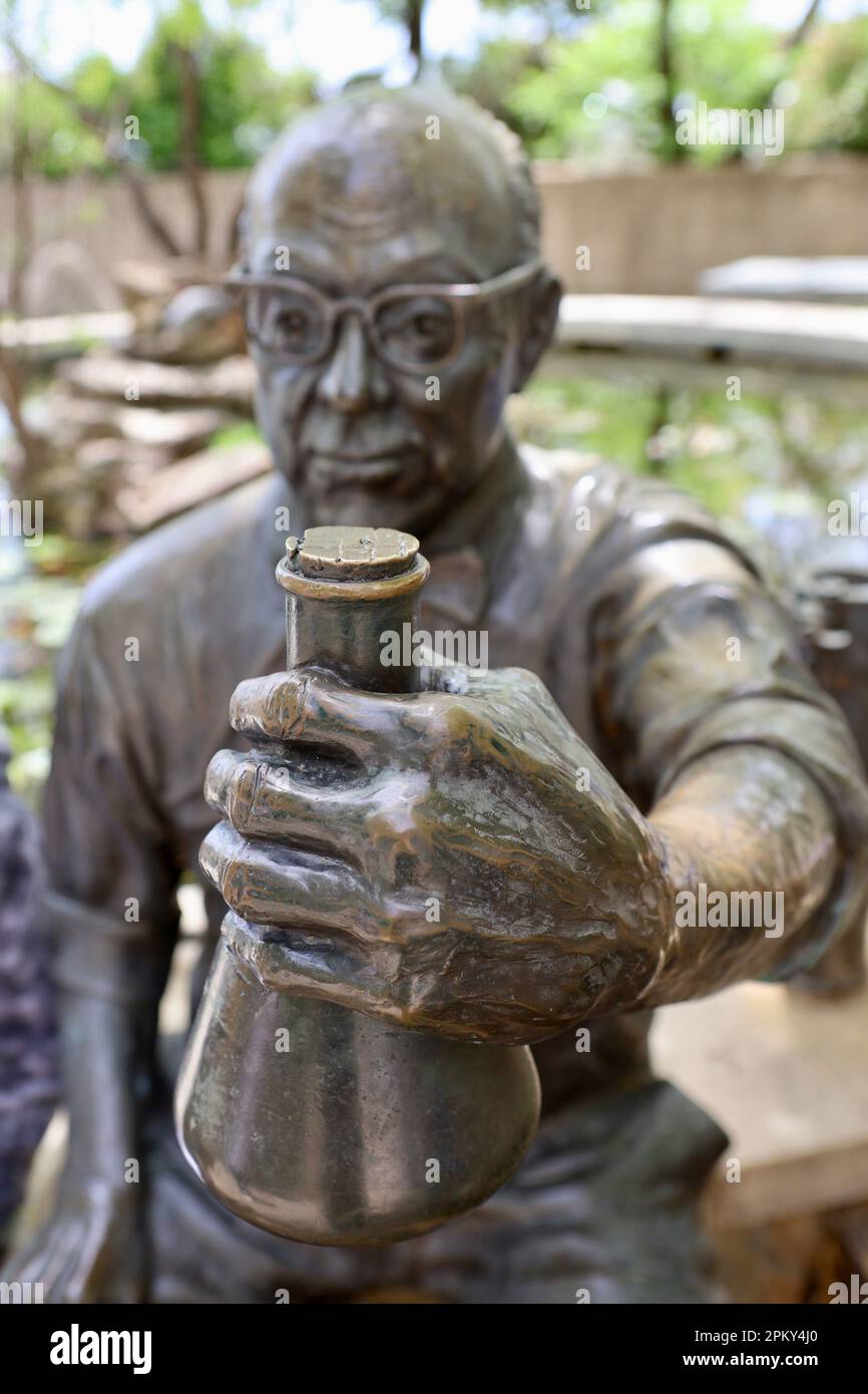 A bronze sculpture of an elderly man holding a container in his hands Stock Photo