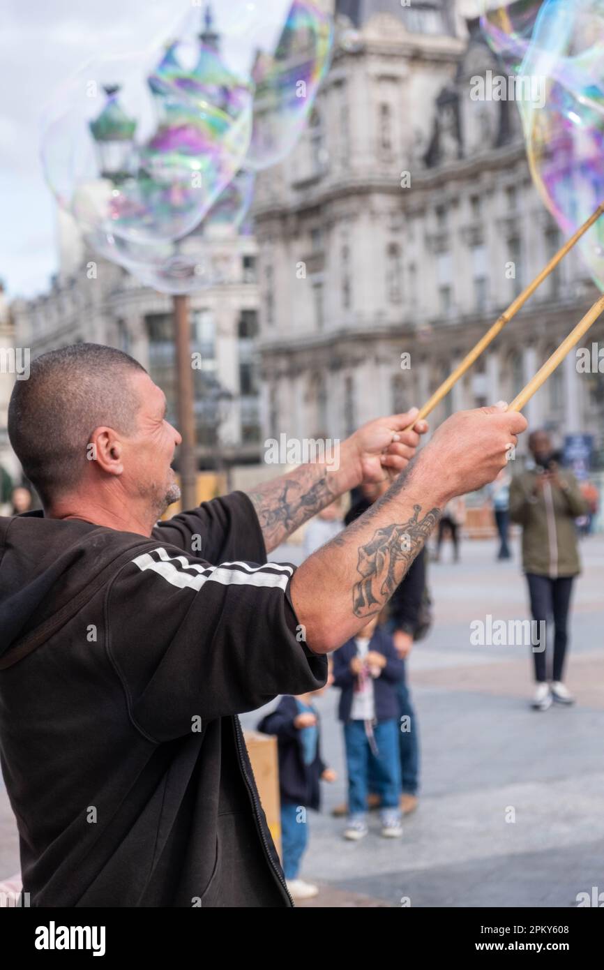 Man blowing many bubbles with two sticks and a rope in Paris, France Stock Photo