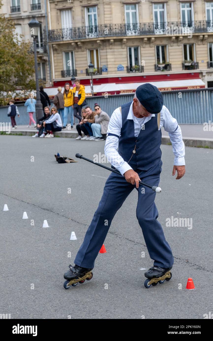 Timeless Showmanship: 60-Year-Old Man in 1940s Attire Executes Impressive Roller Blade Tricks on a Parisian Bridge, Captivating the Onlookers Stock Photo