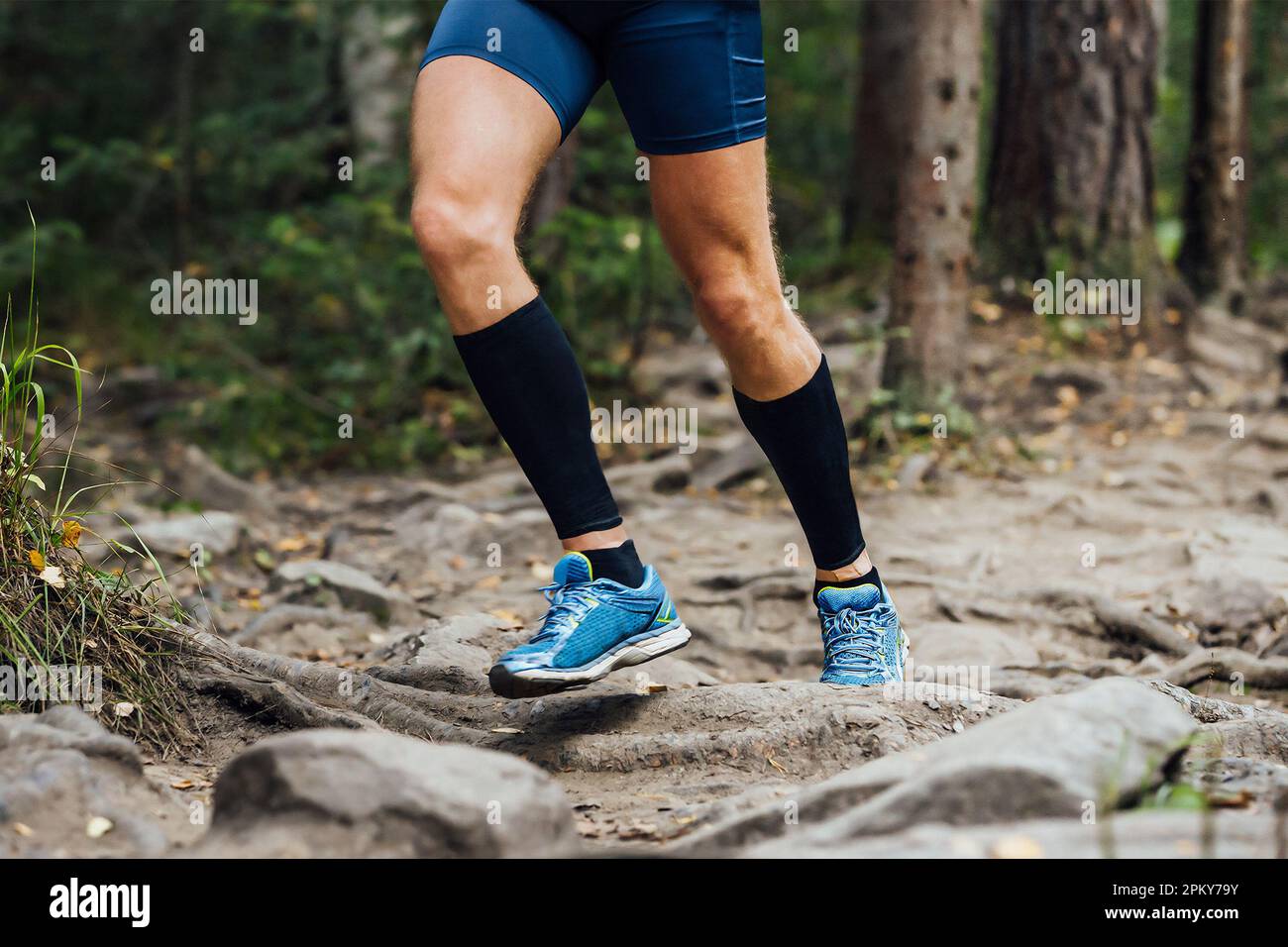 legs runner in compression sleeves on his feet run forest trail race over stones, summer marathon race Stock Photo