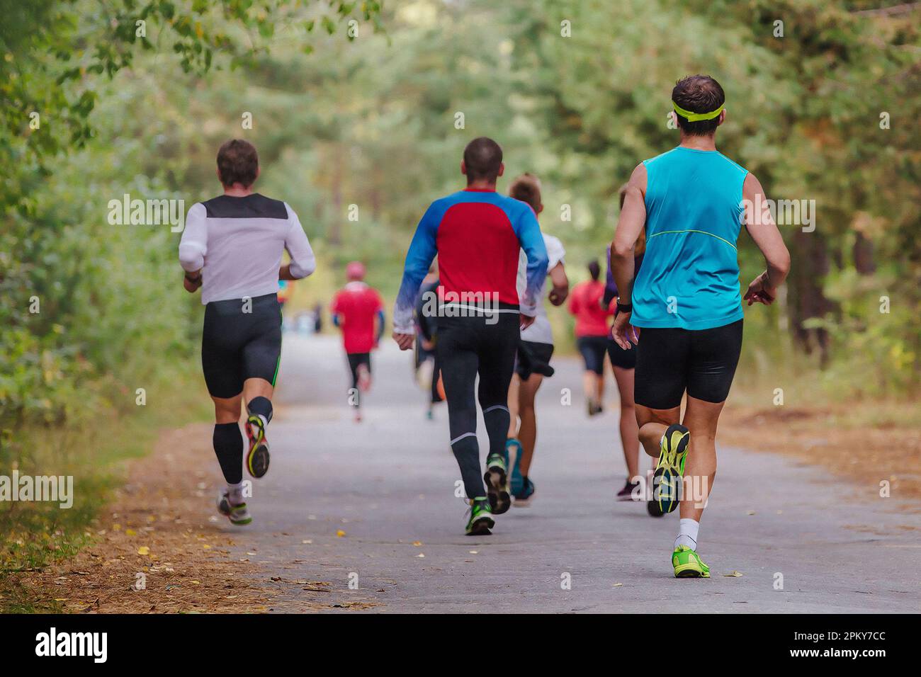 group athletes runners running race on road in park, autumn marathon, fallen yellow leaves on ground Stock Photo