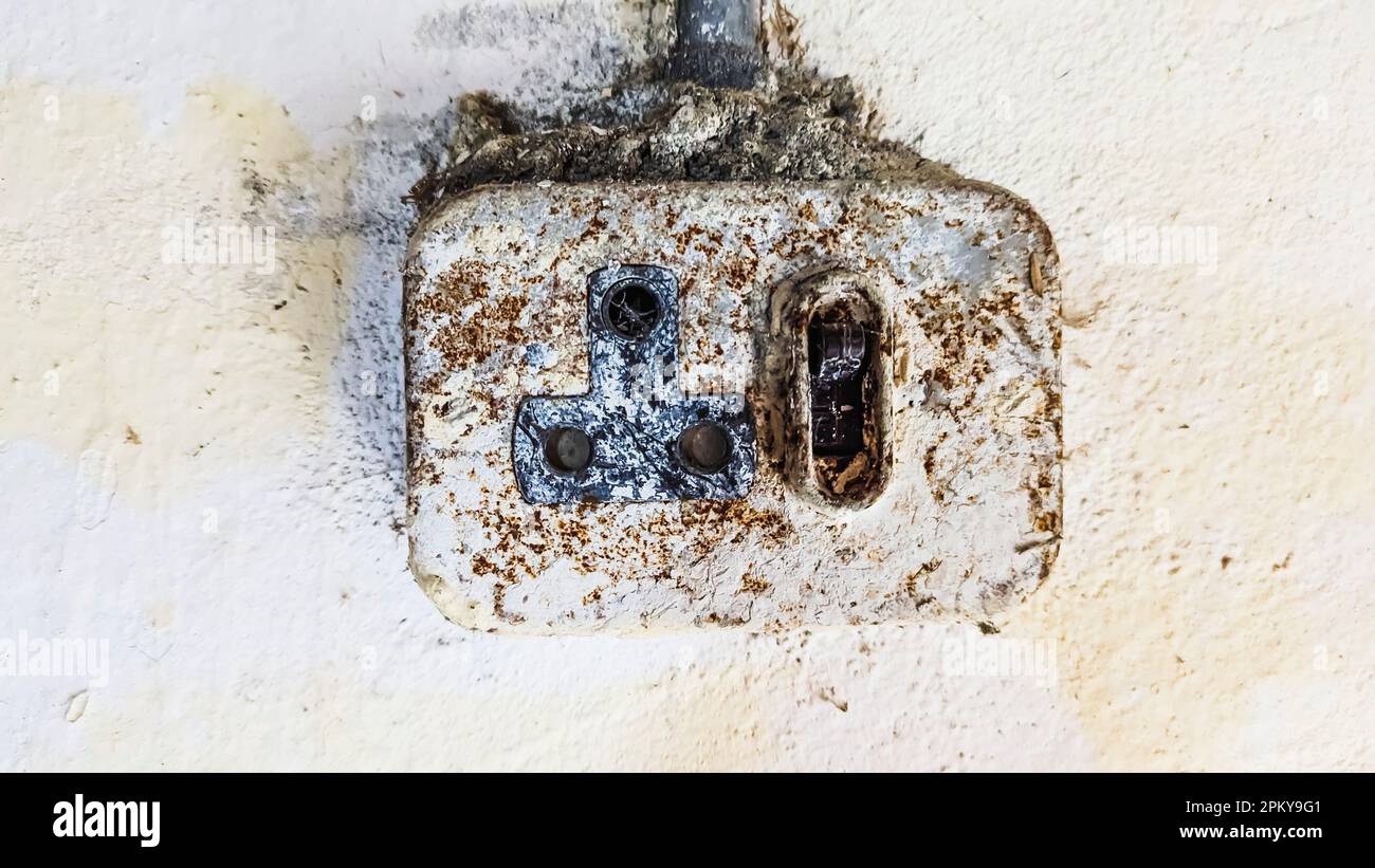 A very old round pin socket covered with rust and dirt on the wall of an old building. Stock Photo