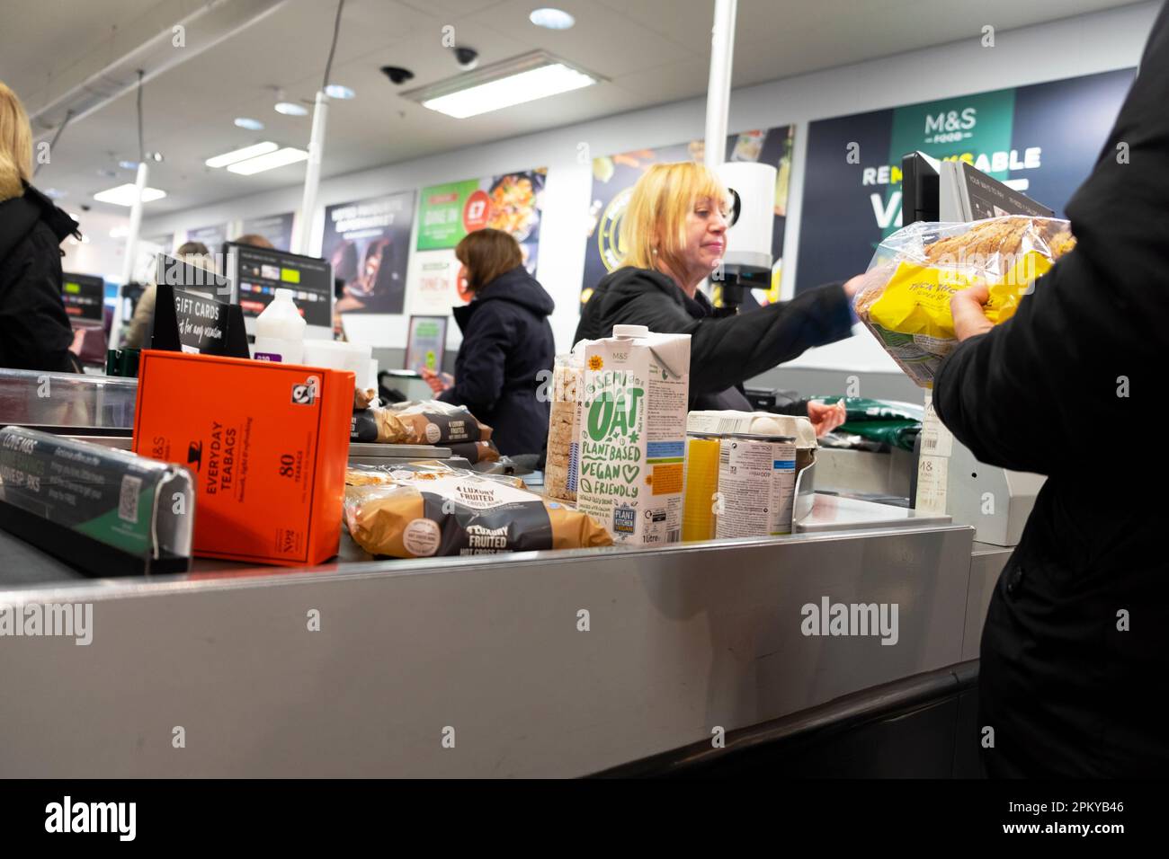 Older employee worker female woman serving custumer oat milk bread at Marks and Spencer M&S