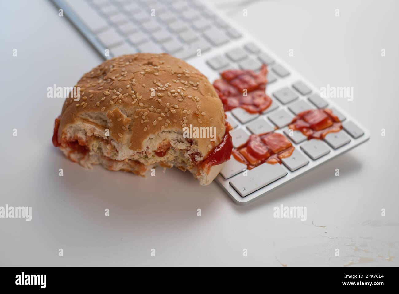 Burger and drops of ketchup on computer keyboard on white desktop Stock ...