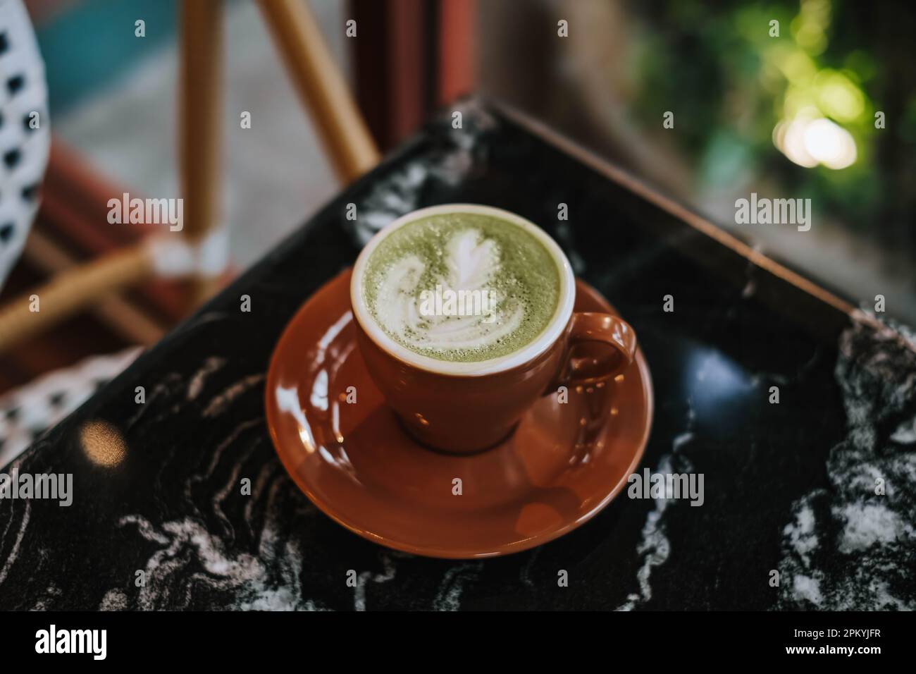 A cup of Matcha Latte with Latte Art on a black marble table. Blurred background. Stock Photo