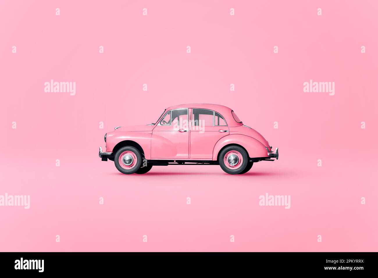 Vintage retro automobile figurine with black wheels parked on pink background in studio Stock Photo