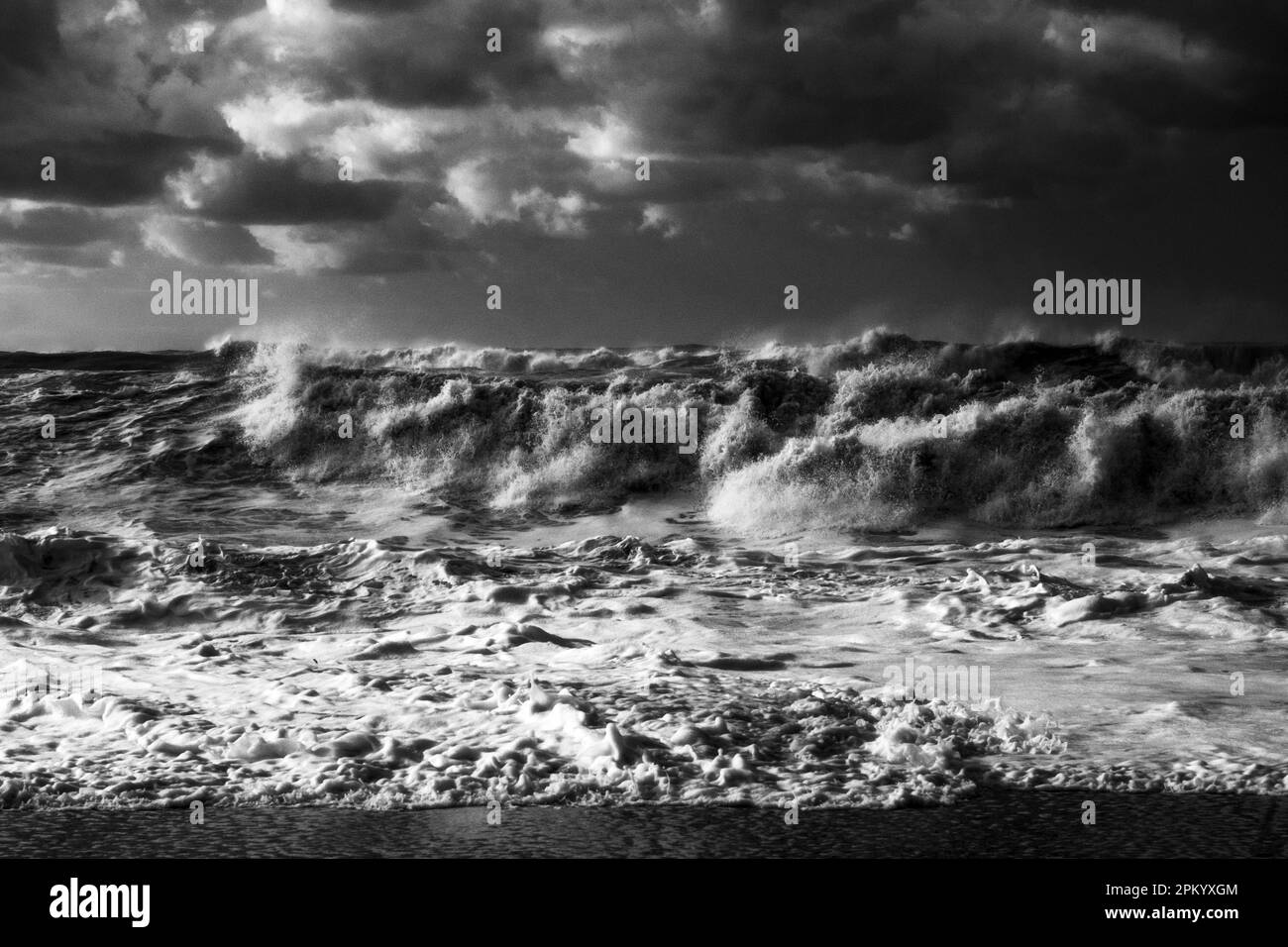 Black and white of powerful foamy waves of stormy sea rolling on sandy ...