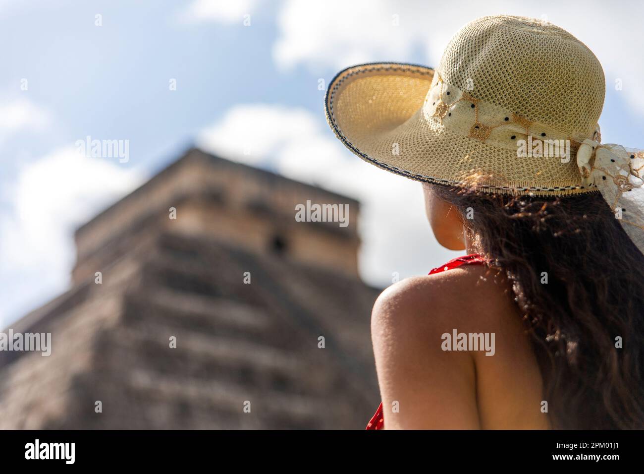 Tourist visiting the pyramid of Chichen Itza in honor of the God Kukulkan the feathered serpent under a beautiful tropical blue sky, the castle of the Stock Photo