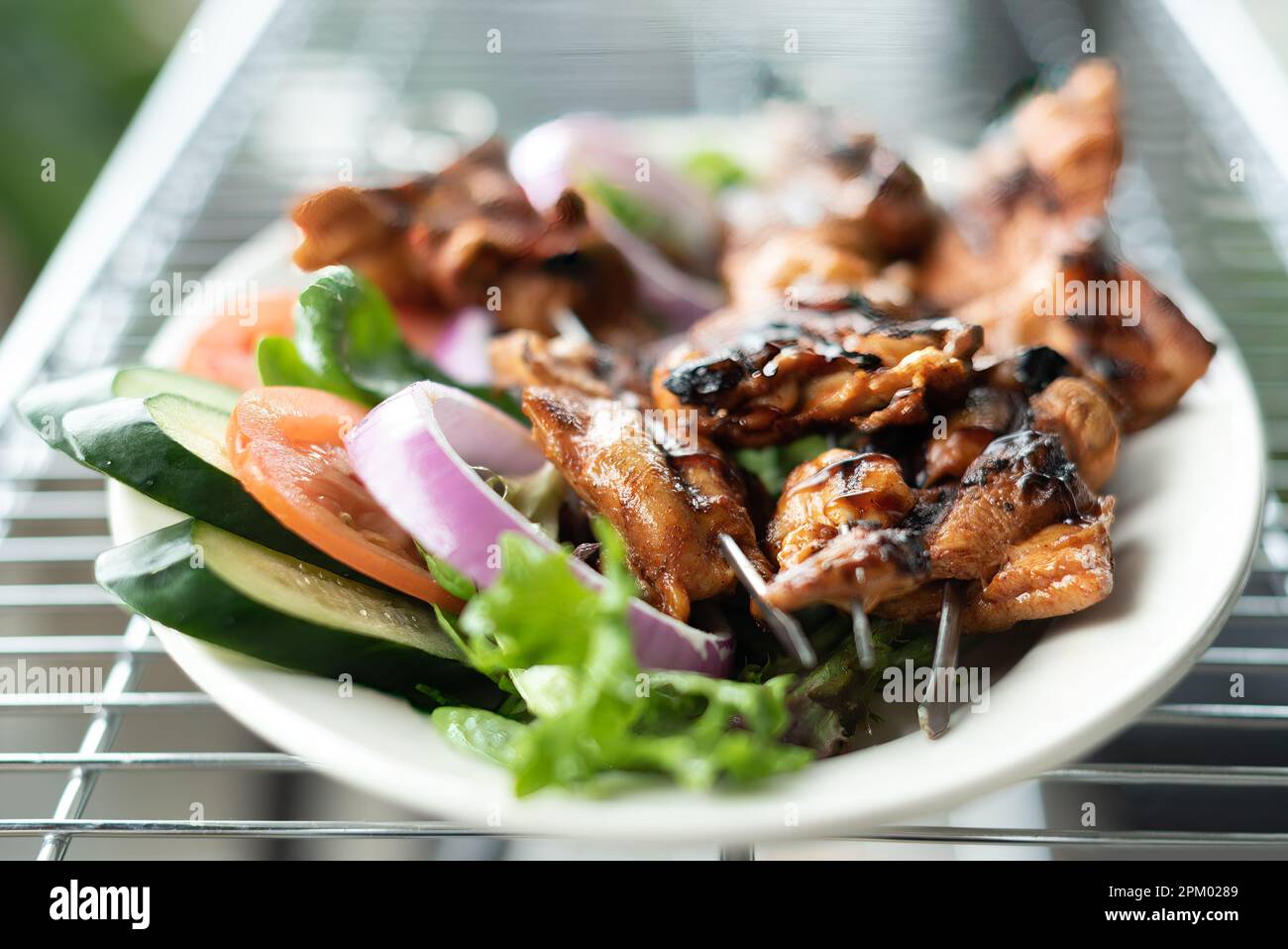 A close-up shot of an appetizing plate of food, featuring a variety of fresh cooked meats and vegetables, with a colorful garnish of herbs Stock Photo