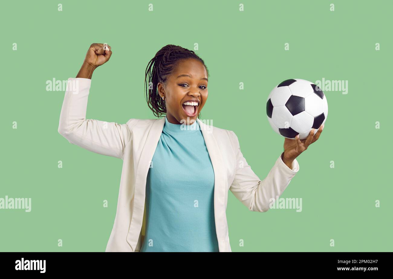 Happy excited young African American woman holding soccer ball and