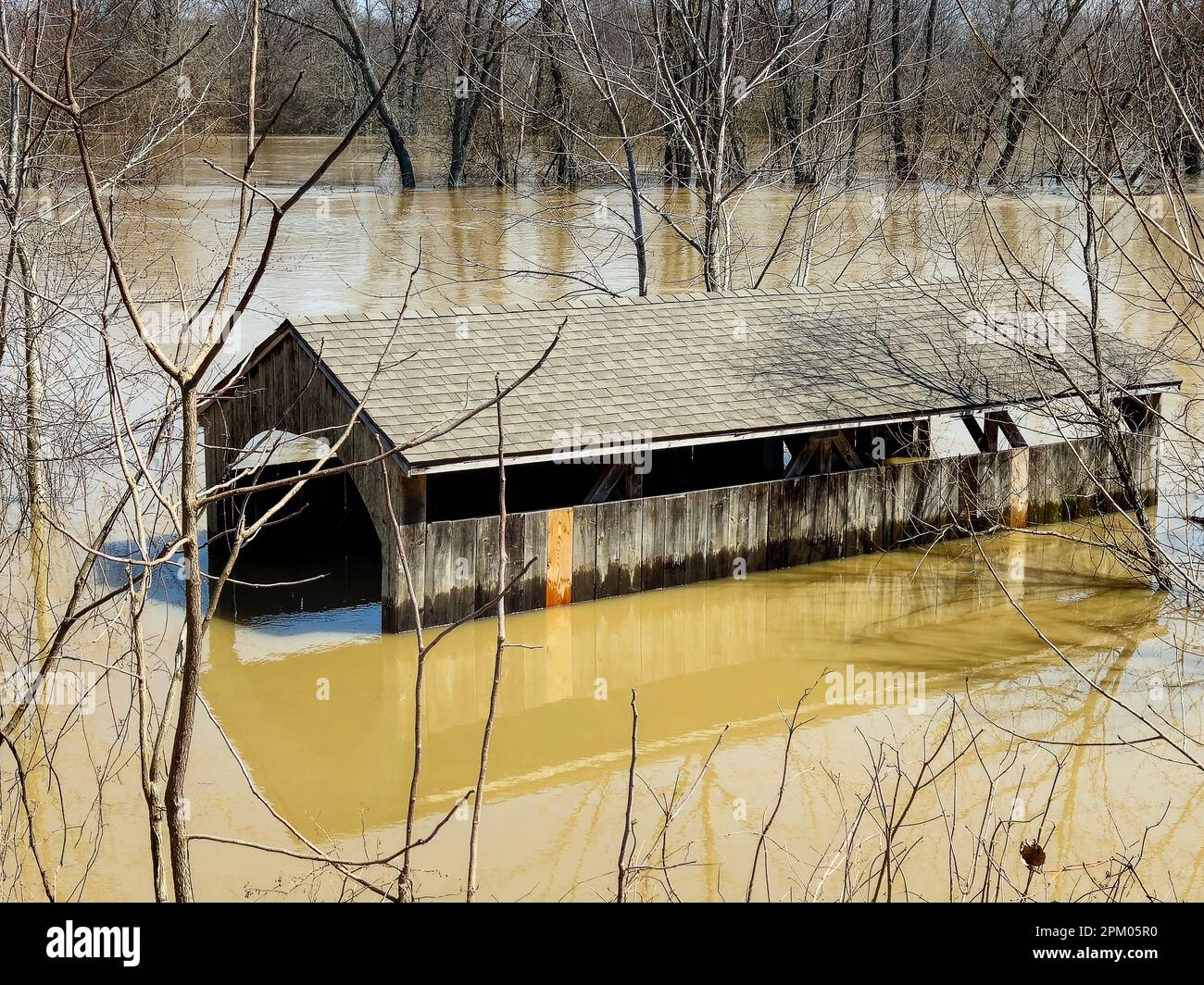 Old Michigan wooden covered bridge in river flood waters in springtime