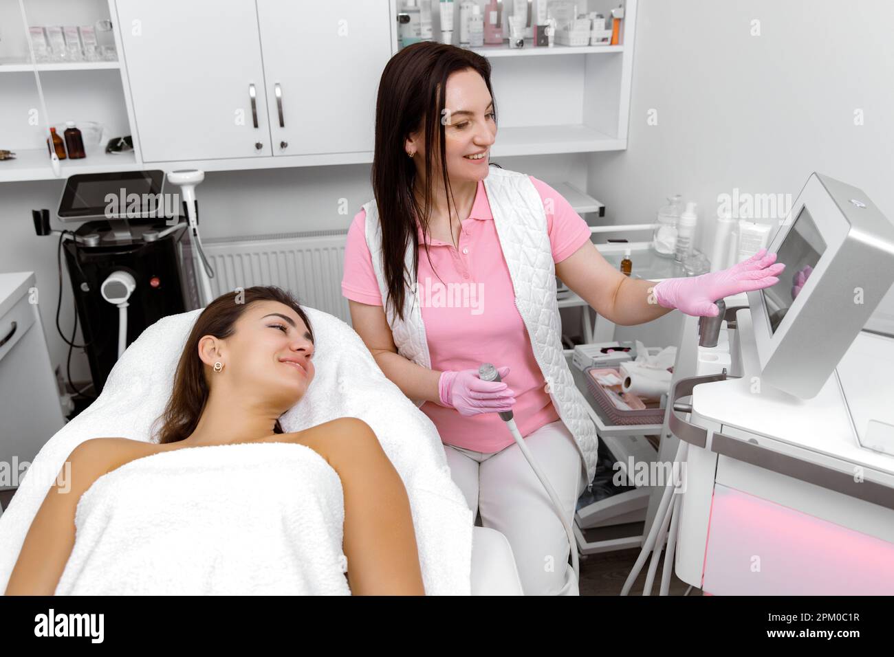 Cosmetology service,Rejuvenation treatment,Skin enhancement service,Cosmetologist consults with the client during the procedure Stock Photo