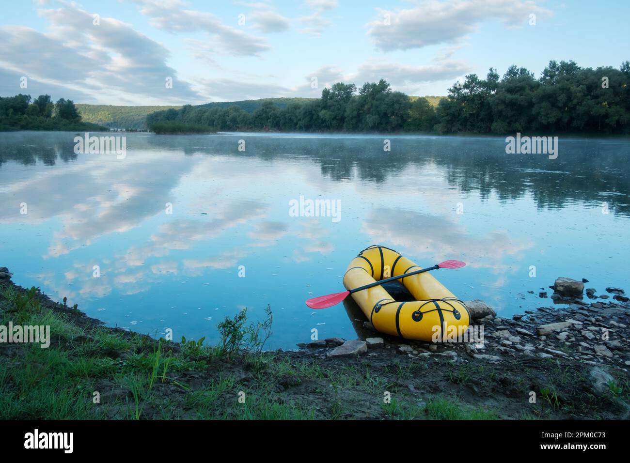 Yellow packraft rubber boat with red padle on a sunrise river. Packrafting. Active lifestile concept Stock Photo