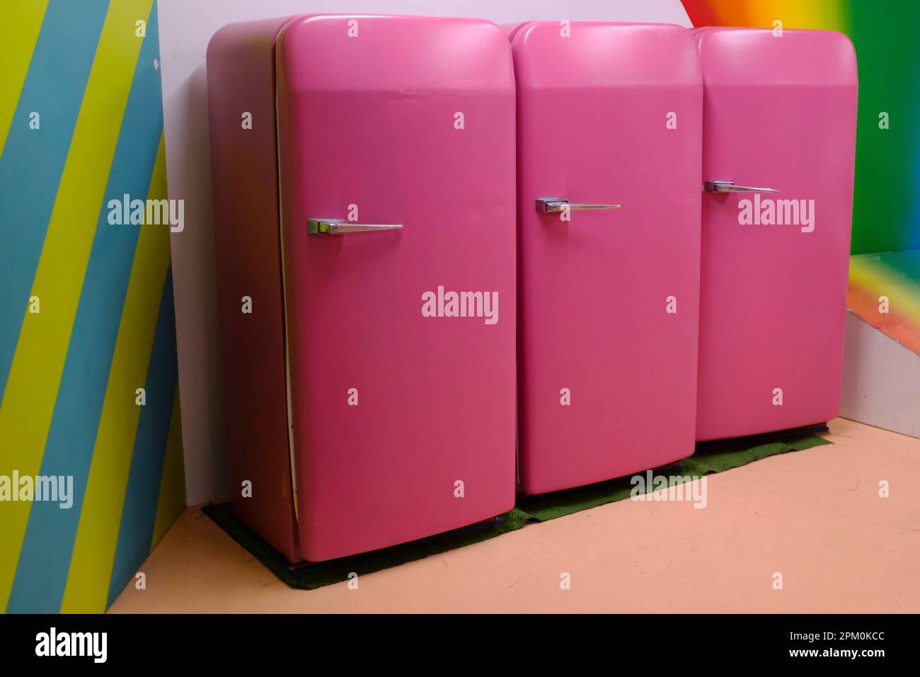 Three pink vintage fridge refrigerator with closed door In a row on a