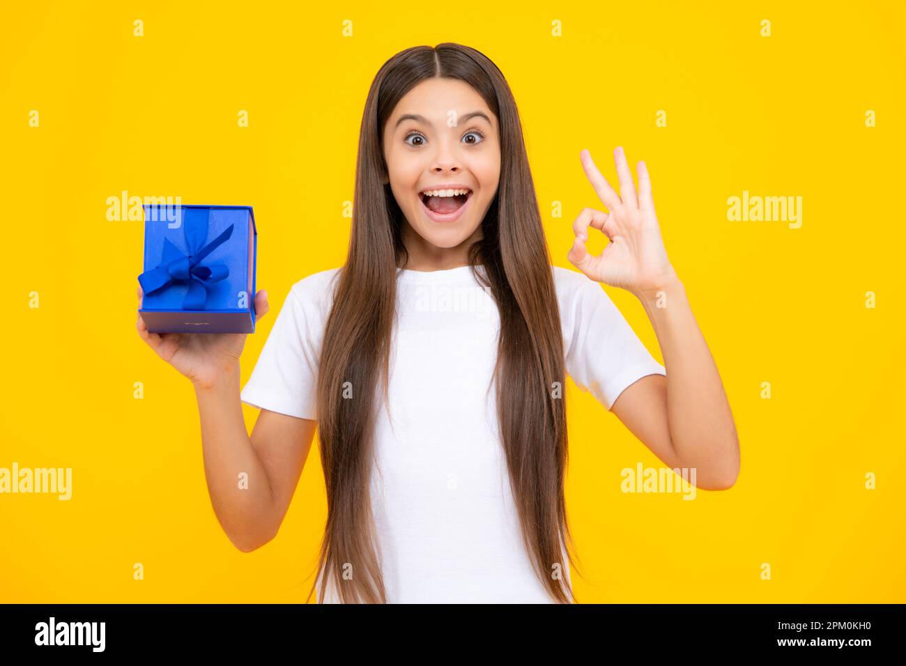 Emotional teenager child hold gift on birthday. Funny kid girl holding gift boxes celebrating happy New Year or Christmas. Excited teenager, glad amaz Stock Photo