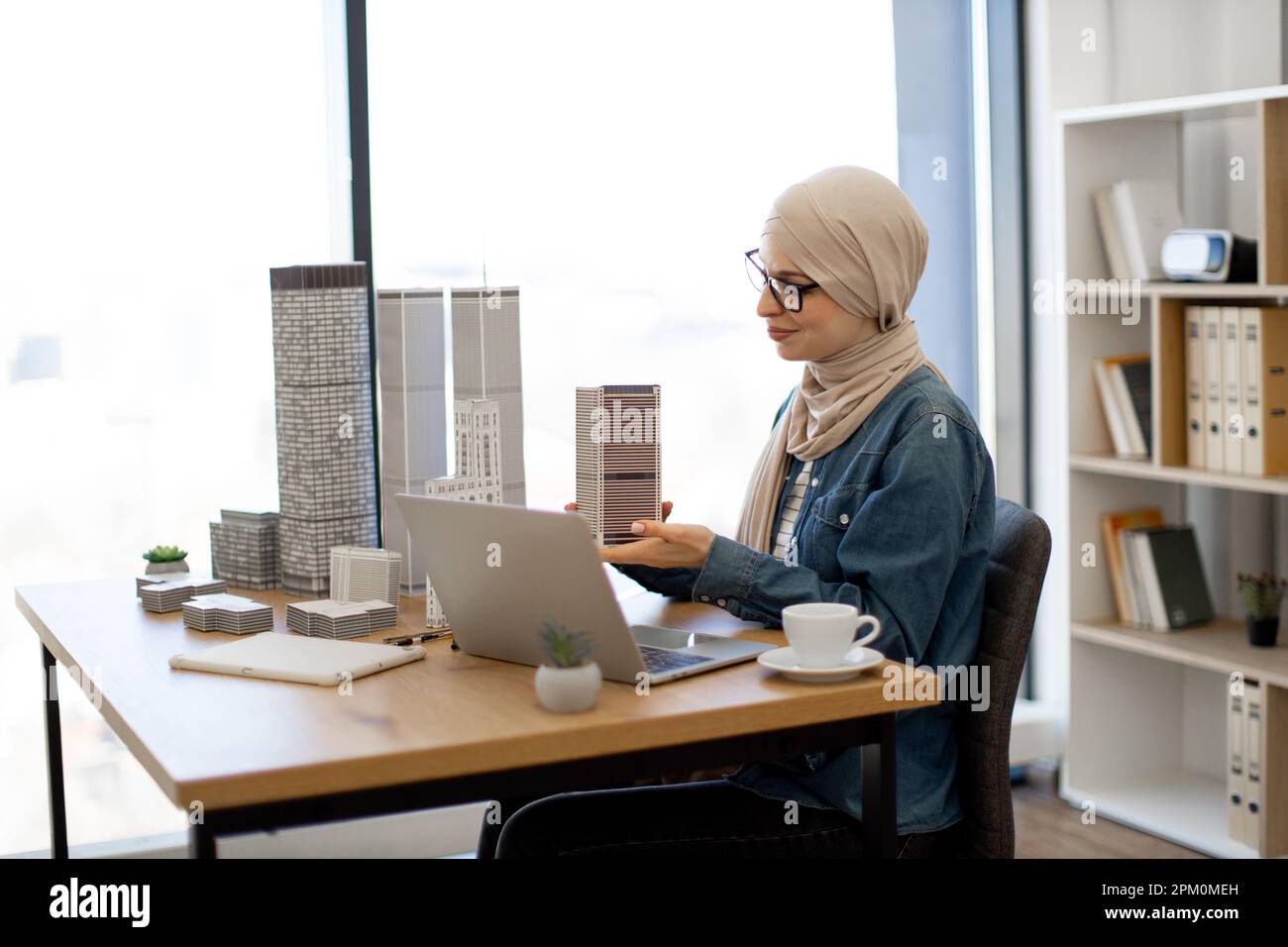 Attractive arabian businesswoman wearing hijab and holding multi-storey ...