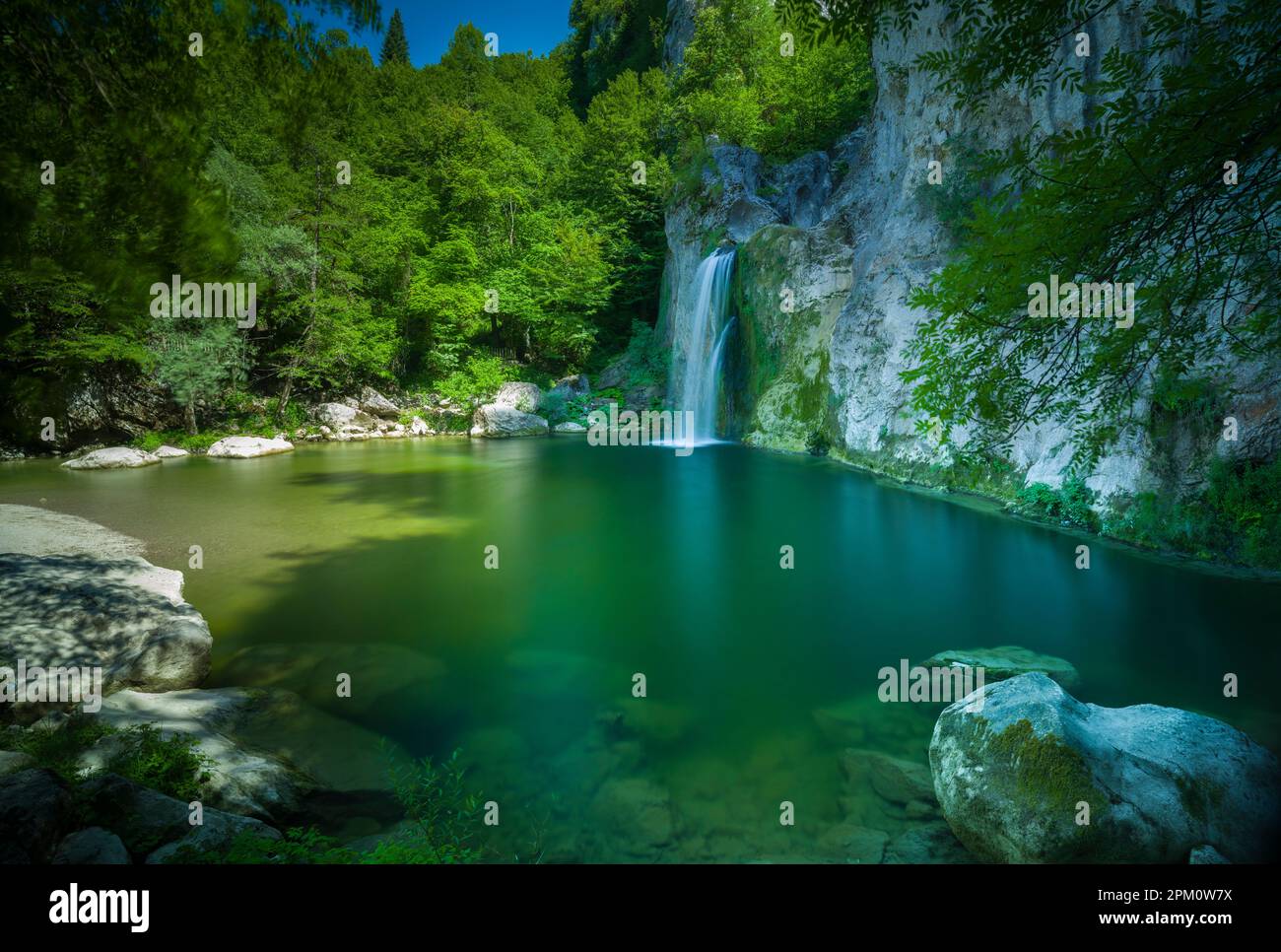 Beautiful landscape. Small lake and forest waterfall. Clear spring water. Nature background. Stock Photo