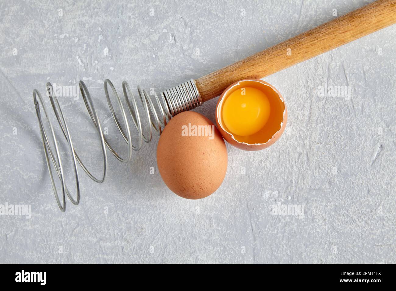 Two beige chicken eggs and a rare beater for beating Stock Photo
