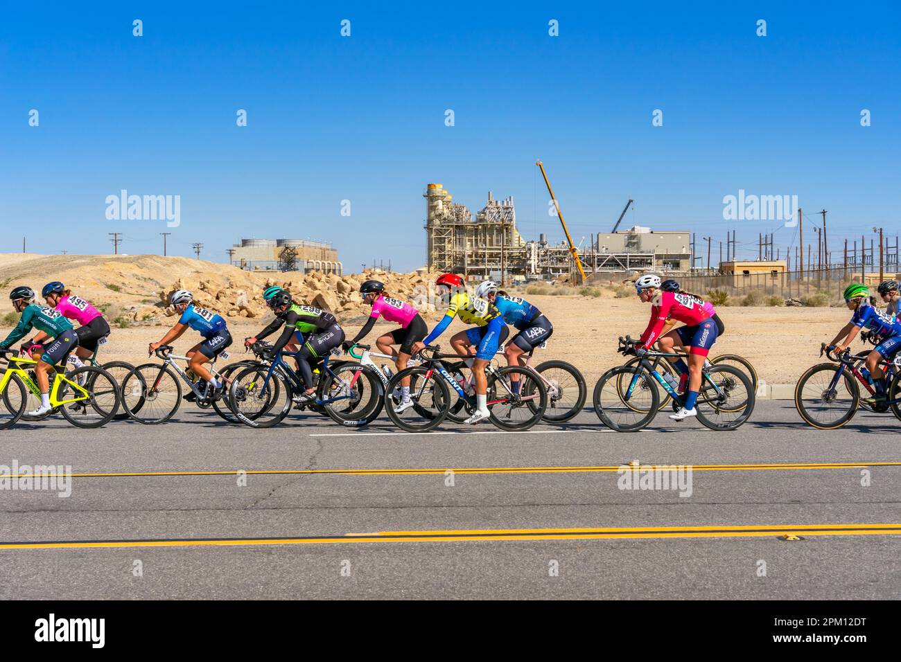 Victorville, CA, USA – March 25, 2023: A group of female cyclist riding pass an industrial area during a cycling road race in Victorville, California. Stock Photo