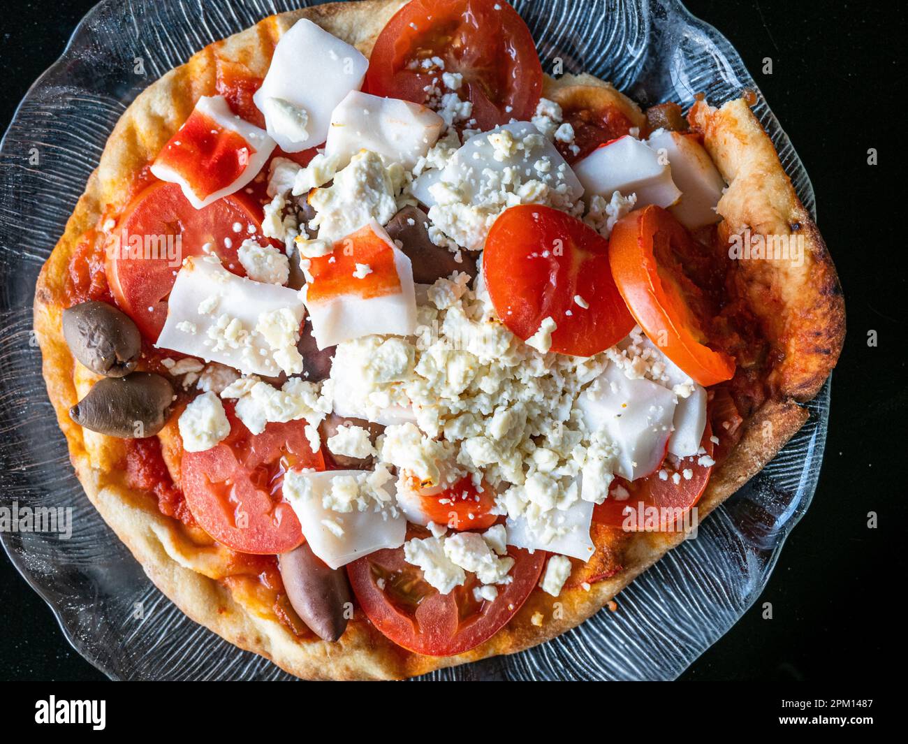 This delicious home made pizza is fairly healthy. It's made of naan bread, tomatoes, black calamata (kalamata) olives, crab sticks and feta cheese. Stock Photo