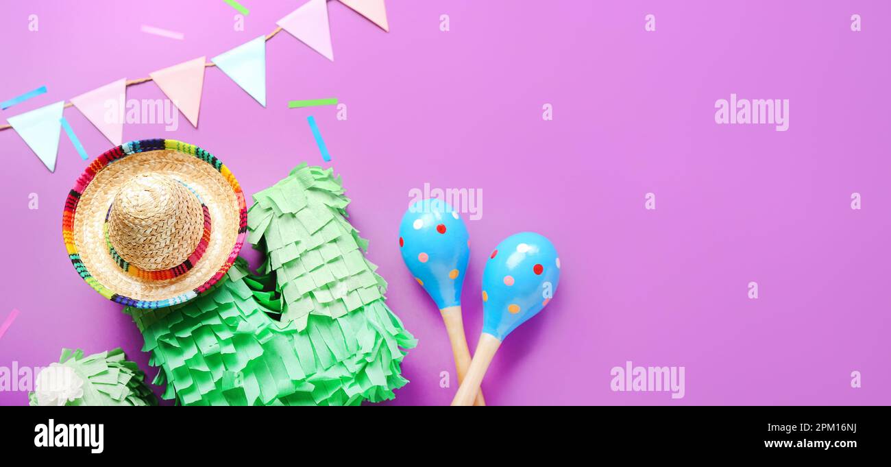 Sombrero, pinata, maracas and Mexican garland on purple background with