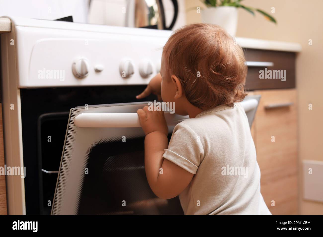 Little child opening oven indoors. Dangers in kitchen Stock Photo Alamy