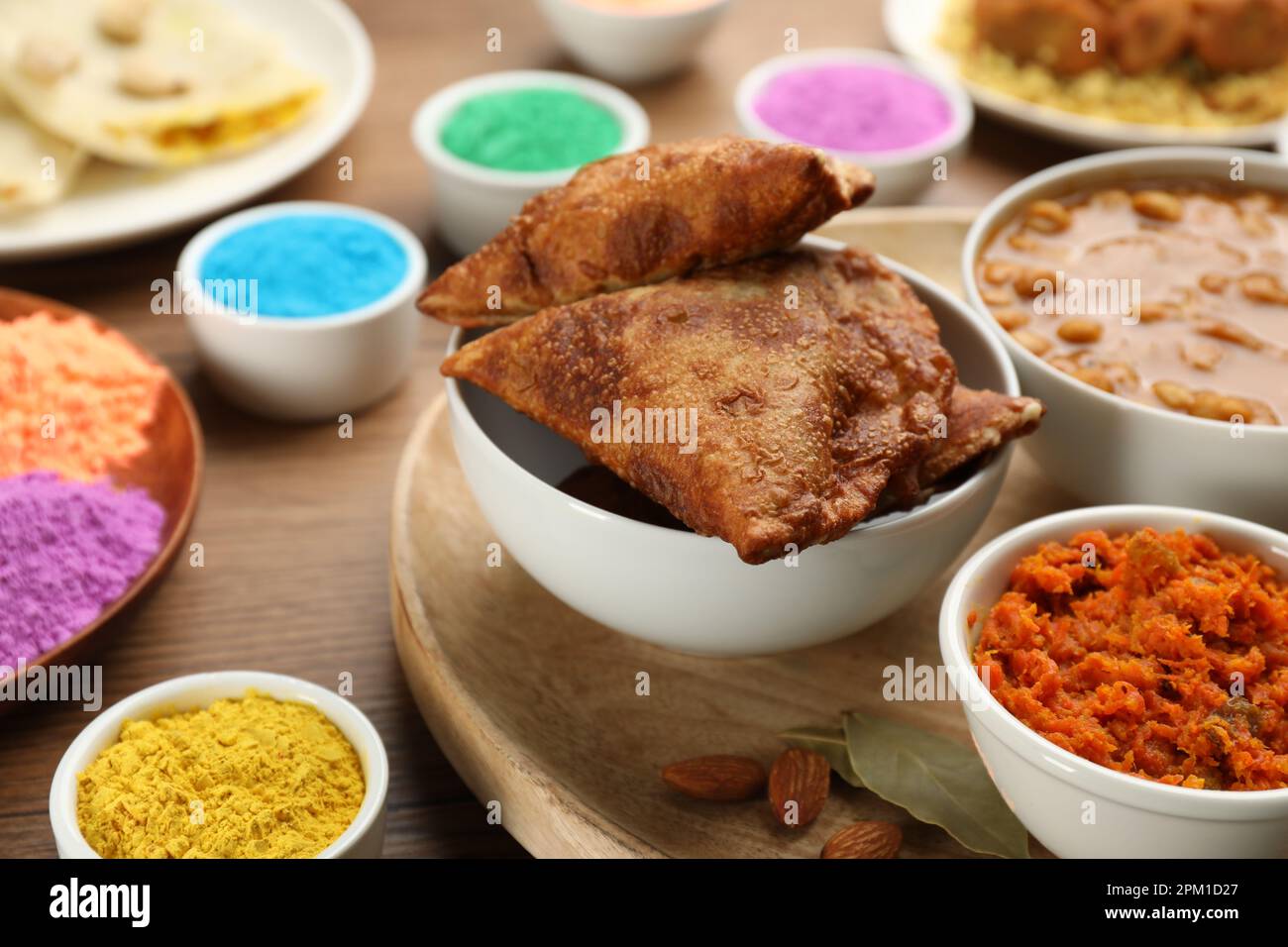 Traditional Indian food and color powders on wooden table, closeup. Holi festival celebration Stock Photo
