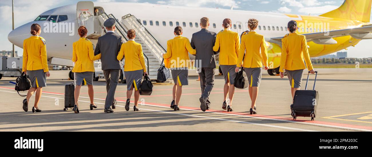 Airline workers with travel bags walking down the airfield Stock Photo