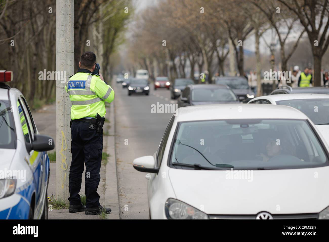 Bucharest, Romania - 8 April, 2023: Romanian Road Police officer uses a radar speed gun on a street in Bucharest Stock Photo