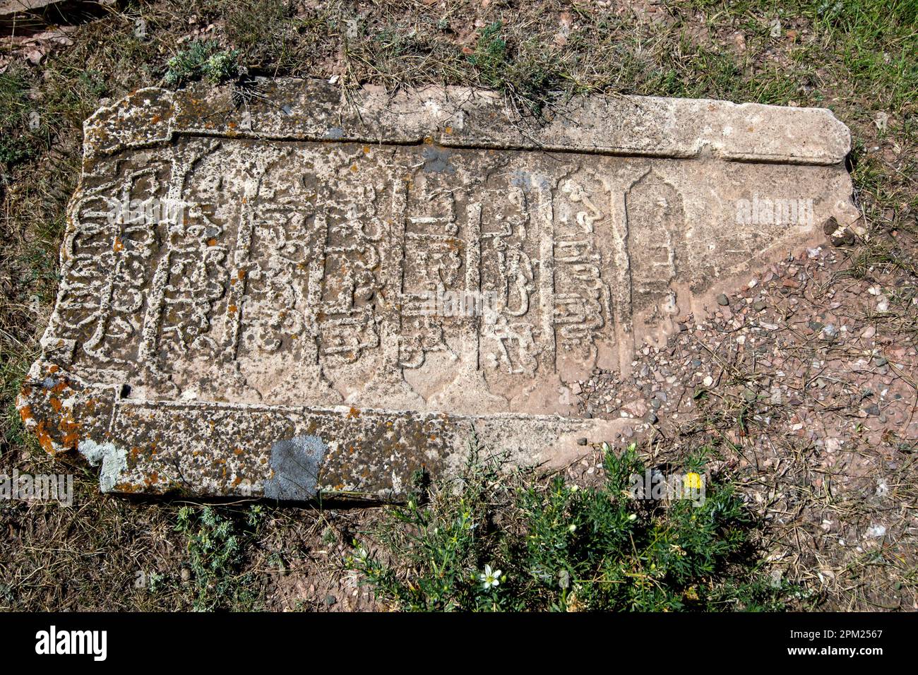 A fallen headstone lays in the abandoned cemetery adjacent to Ishak Pasa Palace at Dogubayazit in eastern Turkiye. Stock Photo