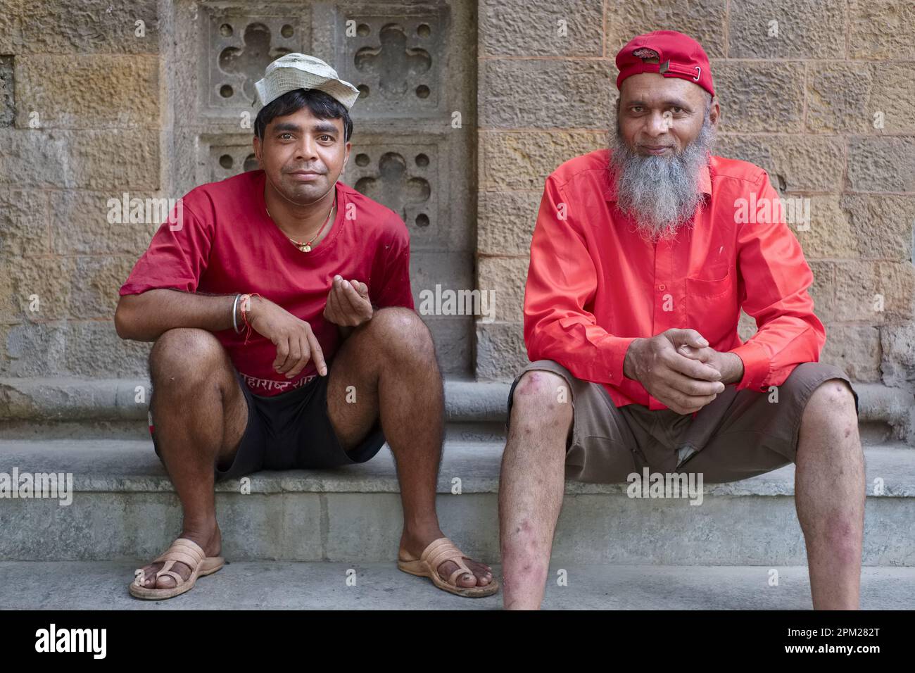 Two friendly porters at Crawford Market Mahatma Jyotiba Phule Market), Mumbai, India, sitting resting; left: a Hindu man, right: a bearded Muslim man Stock Photo