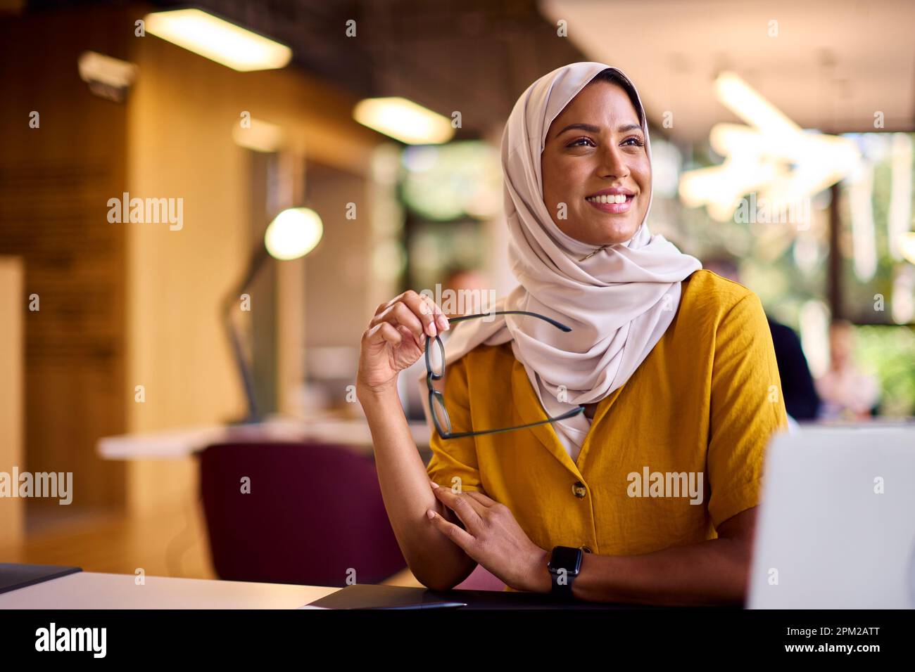 Mature Businesswoman Wearing Headscarf Working On Laptop At Desk In Office Stock Photo