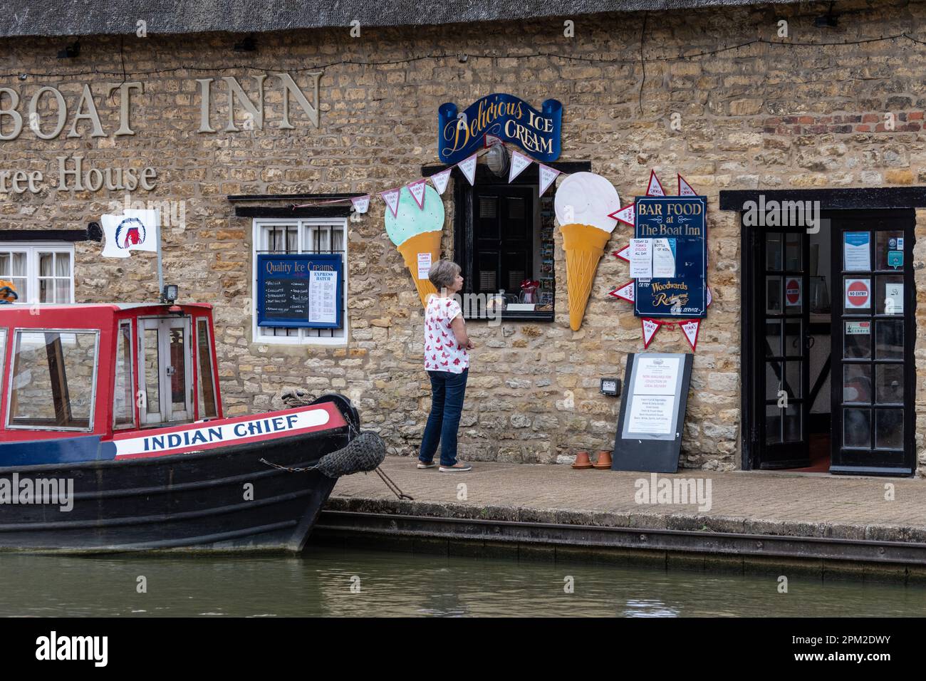 Woman buying ice cream at a window at the Boat Inn, Stoke Bruerne