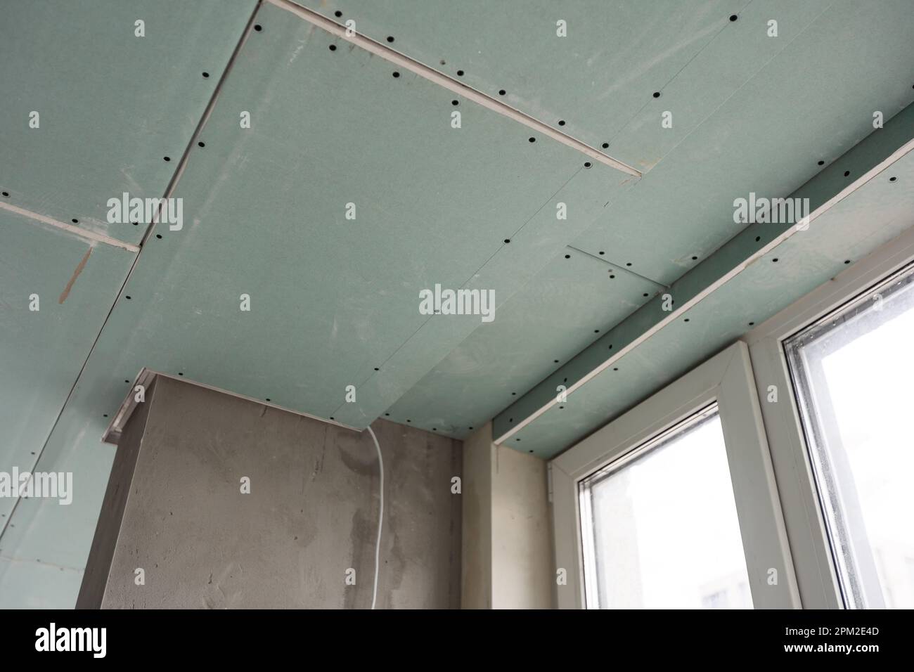 Installation of drywall. Workers are using screws and a screwdriver to