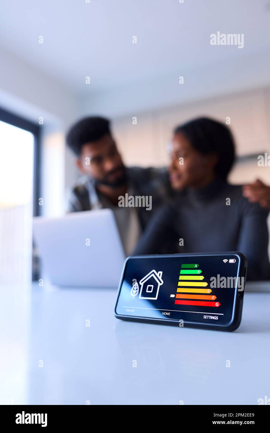 Worried Couple At Home Looking At Laptop With Smart Energy Meter In Foreground Stock Photo