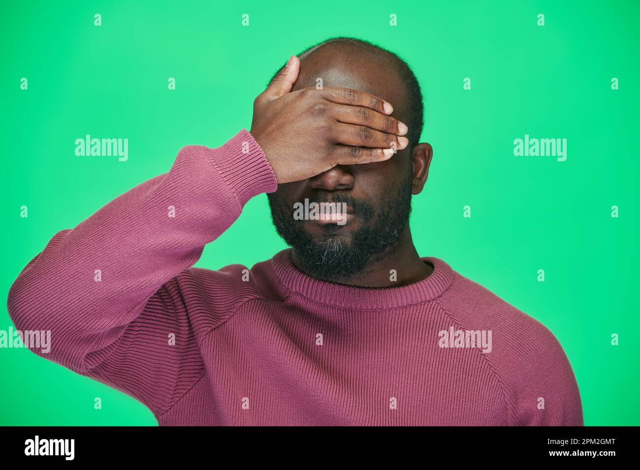 Portrait of African American man covering his eyes with hand standing ...