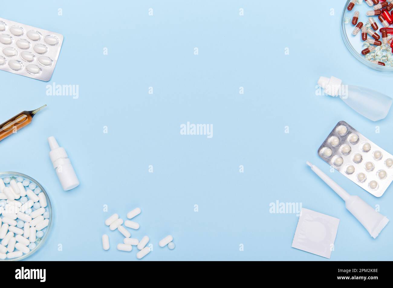 Flat lay. Medical pills, capsules, blisters with dragees, drops and ampoules  laid out on blue background, copy ad space Stock Photo - Alamy