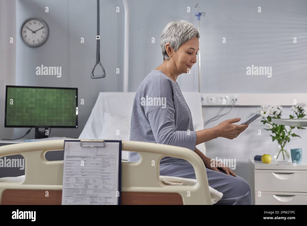 I Using Hospital Mature patient using smartphone for online conversation with her ...