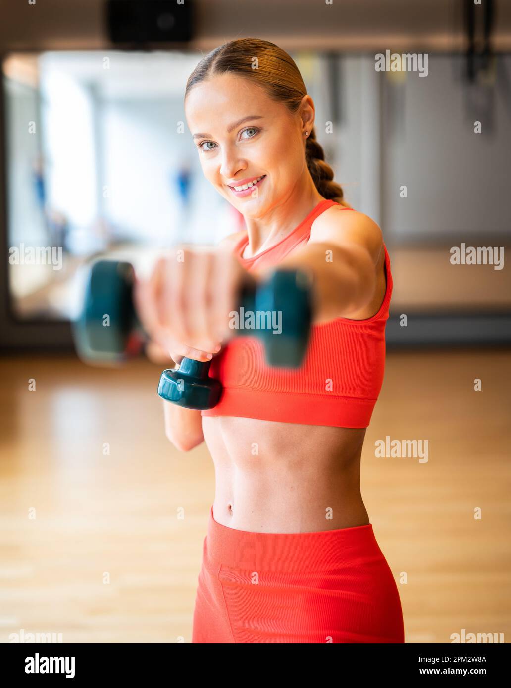 Beautiful young woman lifting dumbbells in a gym Stock Photo