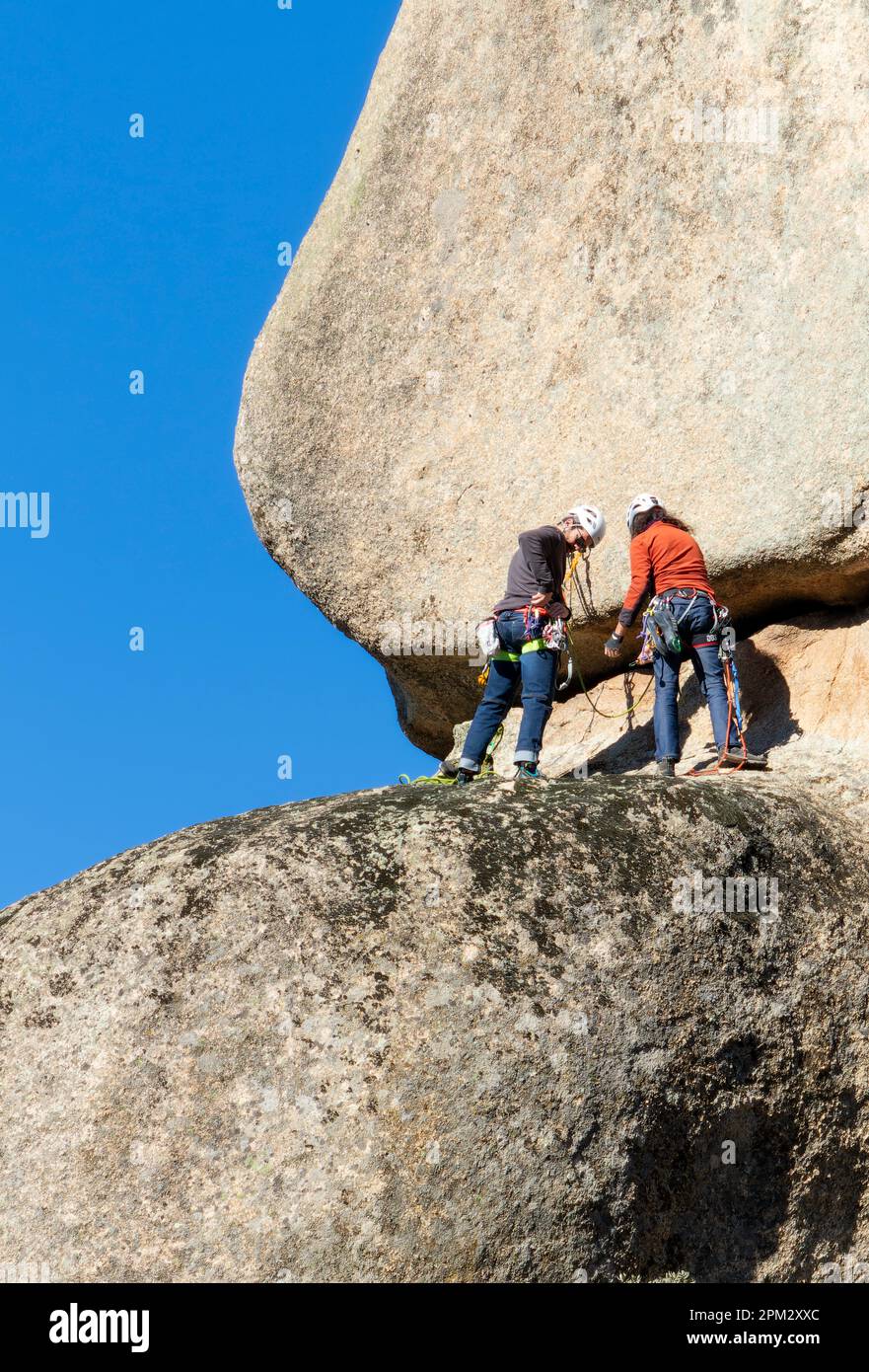 two young adults working together to climb a granite wall. Rock climbing. Extreme sports concept Stock Photo