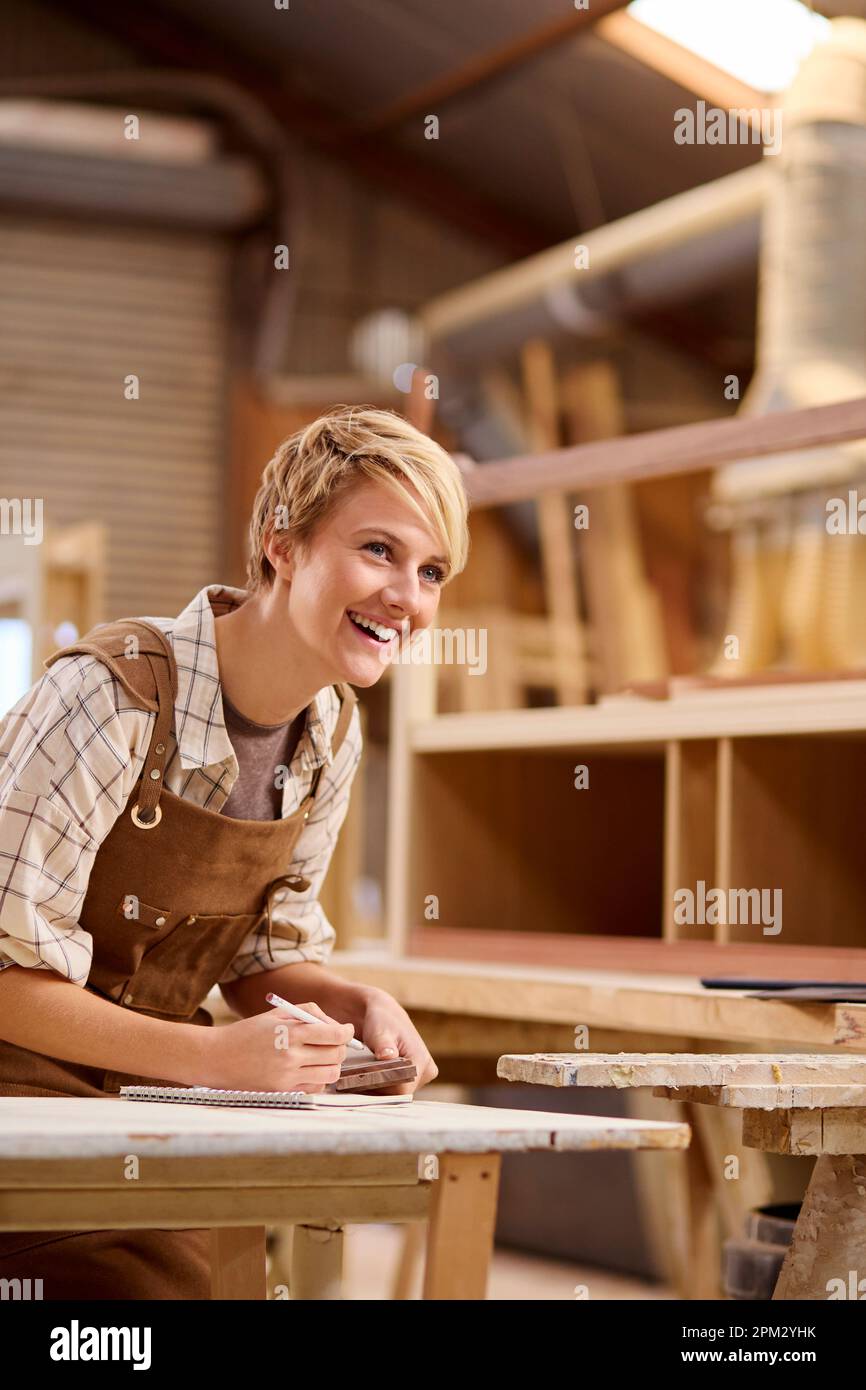 Female Apprentice Working As Carpenter In Furniture Stock