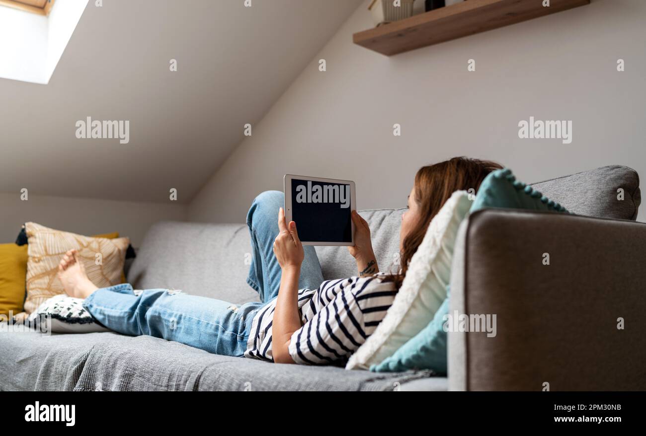 Woman using internet and digital tablet while resting at home. Stock Photo
