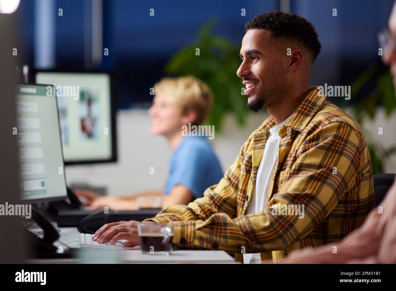 Business Team Using Computers At Desks In Office Working Late Stock Photo