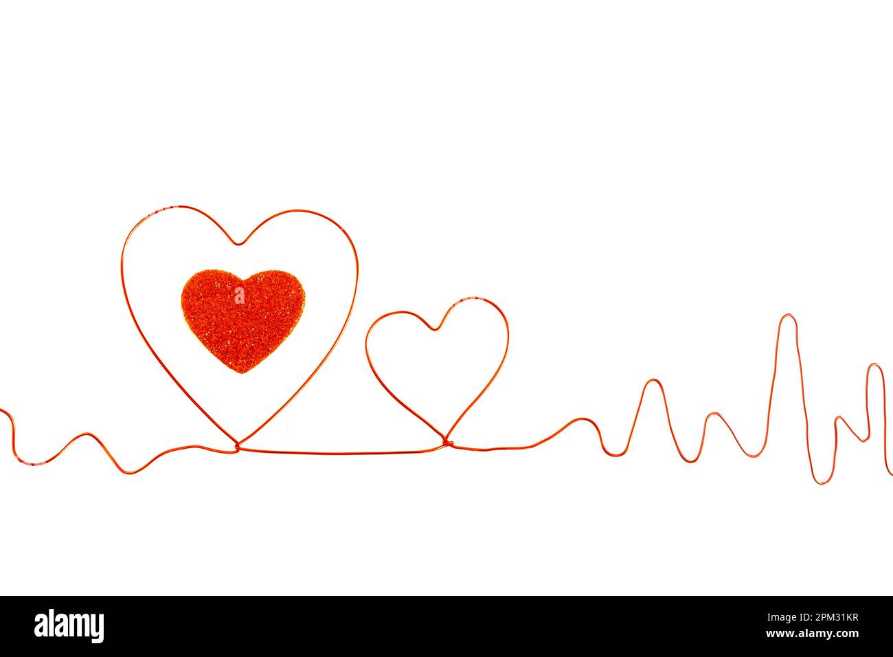 Electrocardiogram, ECG made of red wire making silhouettes of two hearts, one smaller than the other, in the big heart there is a red glitter heart on Stock Photo