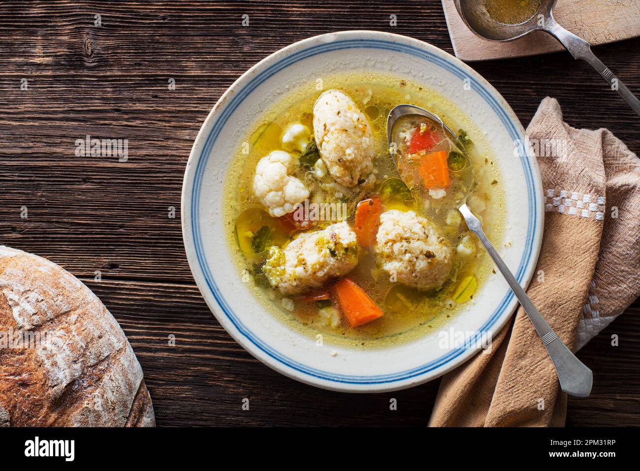 Fresh chicken soup with vegetable and semolina dumplings on wooden background overhead shoot